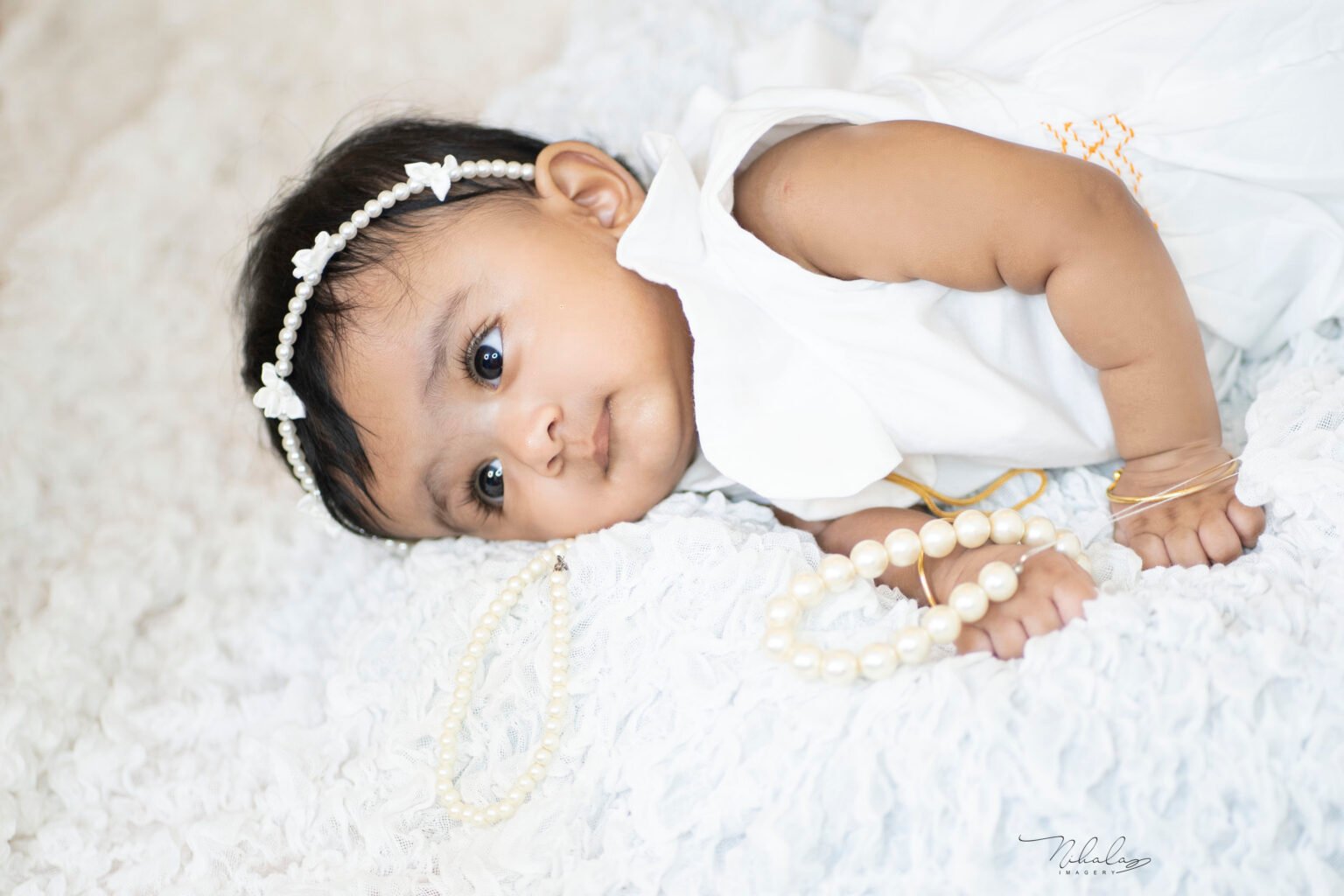 Baby girl with a flower headband on white blanket